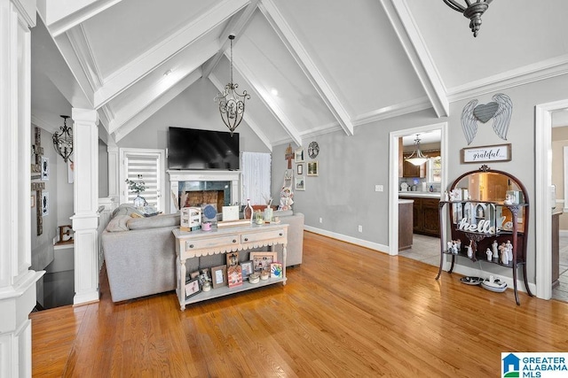 living room with decorative columns, a fireplace, hardwood / wood-style floors, and lofted ceiling with beams