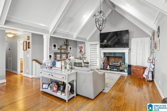 living room with a high end fireplace, lofted ceiling with beams, a notable chandelier, decorative columns, and light hardwood / wood-style floors