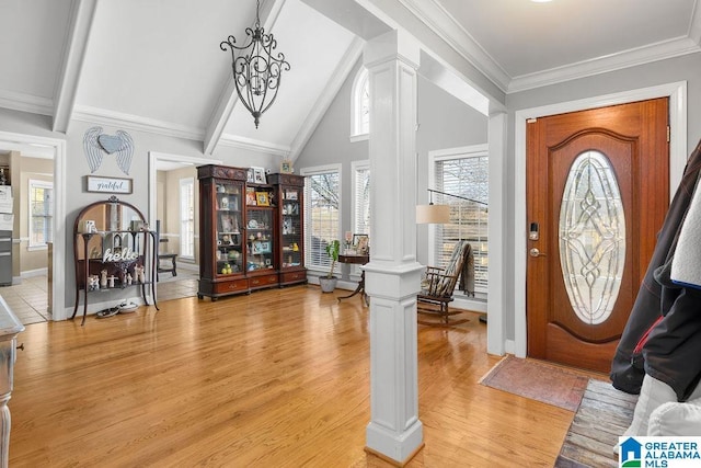 foyer with ornate columns, ornamental molding, vaulted ceiling, hardwood / wood-style flooring, and a notable chandelier