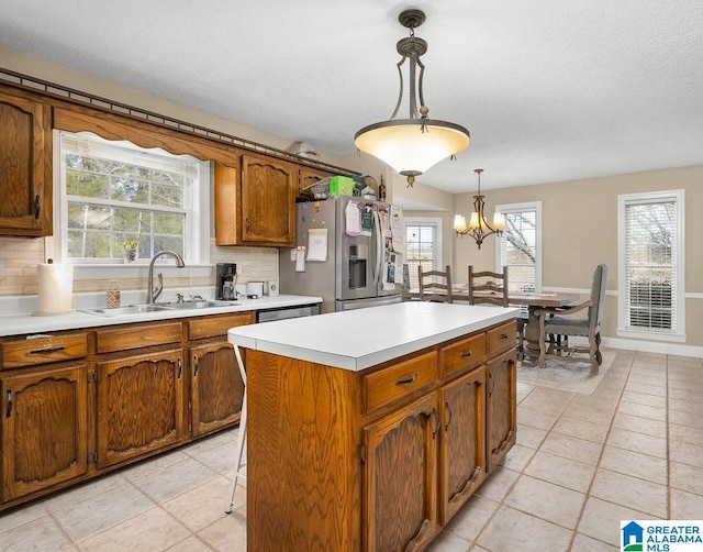 kitchen with decorative backsplash, stainless steel appliances, sink, decorative light fixtures, and a kitchen island