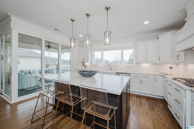 kitchen with a kitchen breakfast bar, pendant lighting, dark hardwood / wood-style flooring, white cabinetry, and a kitchen island