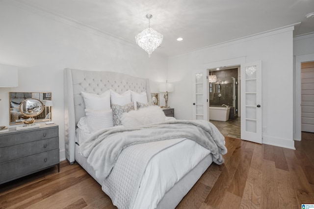 bedroom with an inviting chandelier, hardwood / wood-style floors, crown molding, and connected bathroom