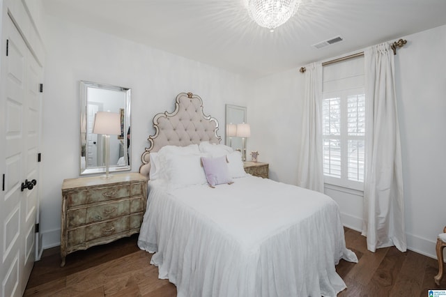 bedroom with a chandelier and dark wood-type flooring