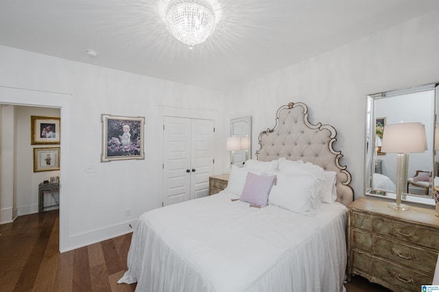 bedroom with a closet, an inviting chandelier, and dark hardwood / wood-style floors