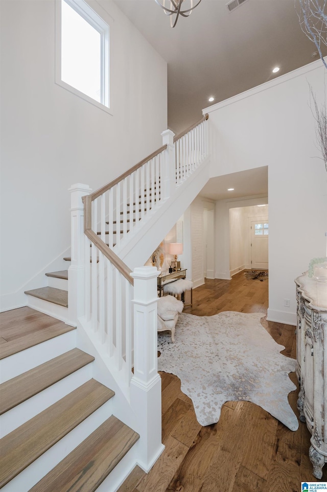 stairway featuring a high ceiling, wood-type flooring, and a chandelier