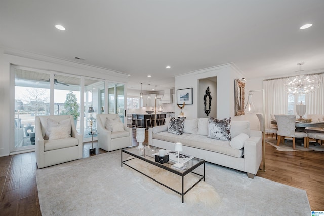 living room featuring wood-type flooring, crown molding, and a chandelier