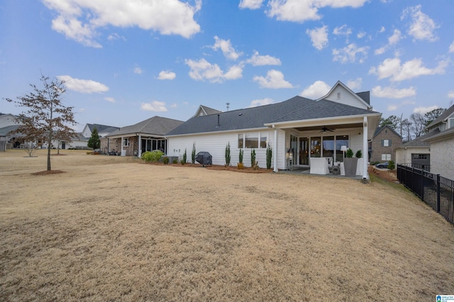 rear view of property featuring ceiling fan and a yard