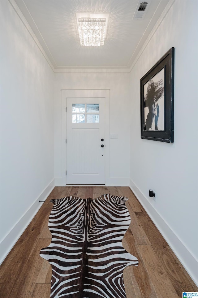 foyer entrance featuring a notable chandelier, hardwood / wood-style flooring, and ornamental molding