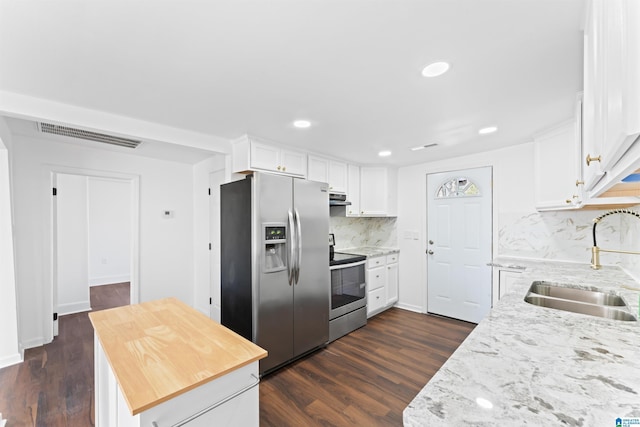 kitchen with appliances with stainless steel finishes, tasteful backsplash, light stone counters, sink, and white cabinetry