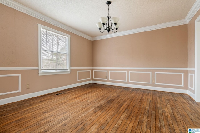 spare room featuring hardwood / wood-style floors, an inviting chandelier, and ornamental molding