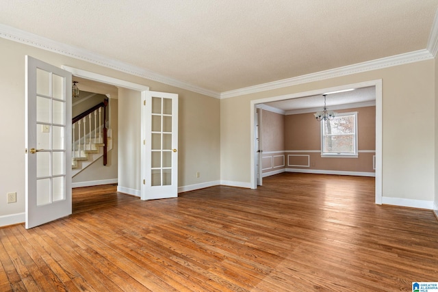 unfurnished room featuring a textured ceiling, a chandelier, french doors, ornamental molding, and wood-type flooring