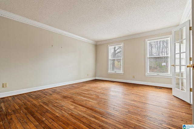 empty room featuring crown molding, light wood-type flooring, french doors, and a textured ceiling