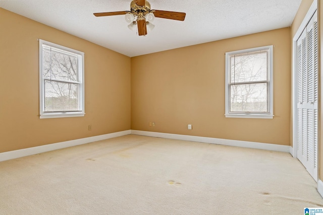 unfurnished bedroom with a closet, a textured ceiling, ceiling fan, and light carpet