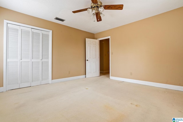 unfurnished bedroom featuring light carpet, a closet, and ceiling fan