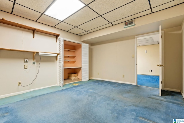 unfurnished bedroom with a drop ceiling, a closet, and carpet