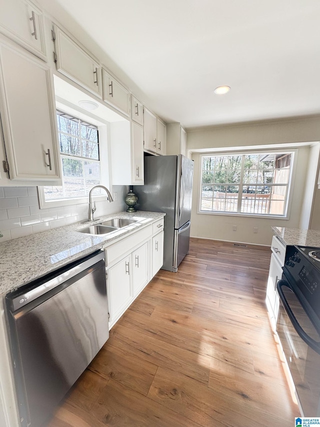 kitchen with sink, stainless steel dishwasher, white cabinets, and black / electric stove