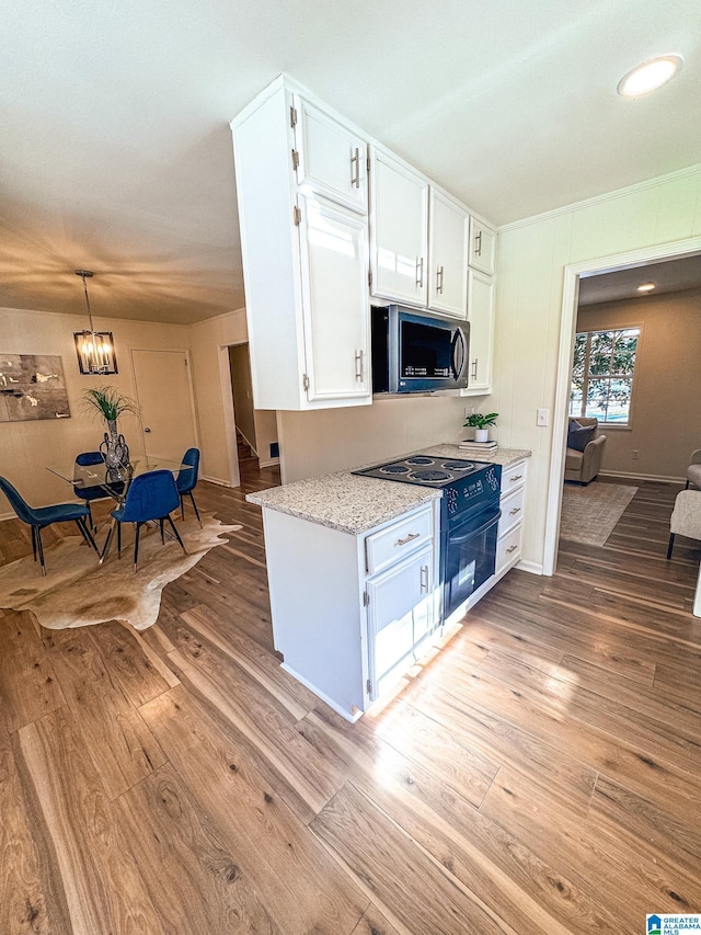 kitchen with decorative light fixtures, white cabinetry, light hardwood / wood-style flooring, black / electric stove, and light stone counters