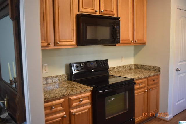 kitchen with black appliances, dark hardwood / wood-style floors, and light stone counters