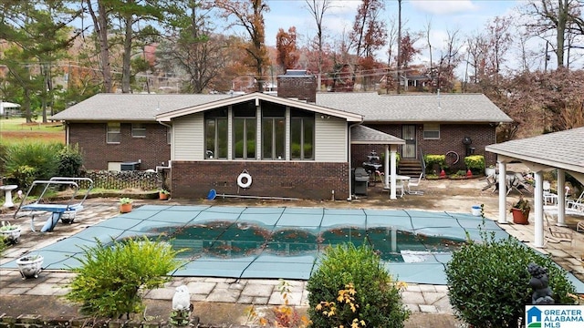 back of house with a covered pool and a patio area