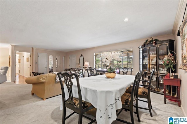 carpeted dining room with ornamental molding