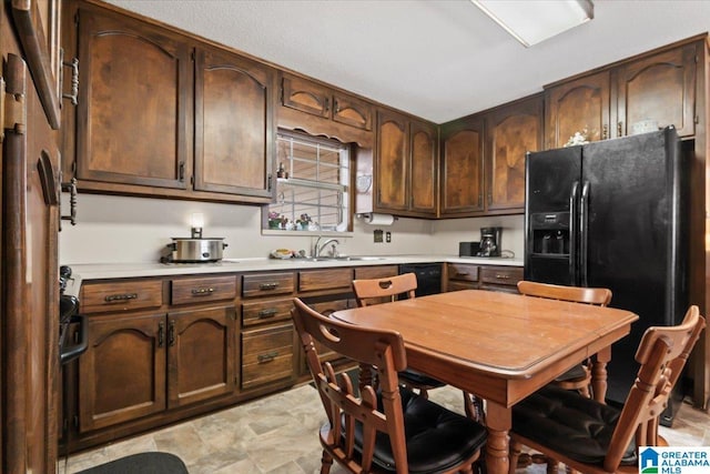 kitchen featuring dark brown cabinetry, black fridge, refrigerator, and sink