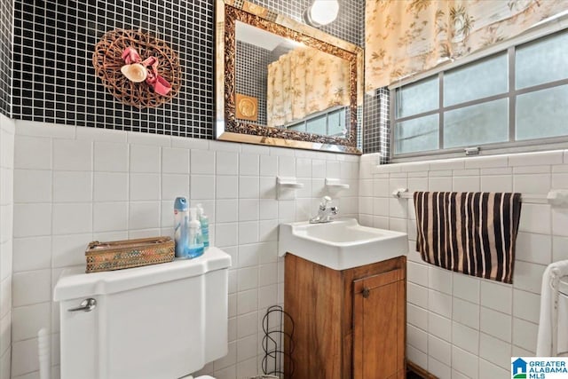 bathroom with vanity, toilet, and tile walls