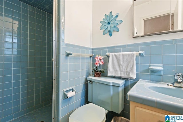 bathroom with vanity, toilet, a shower with shower door, and tile walls