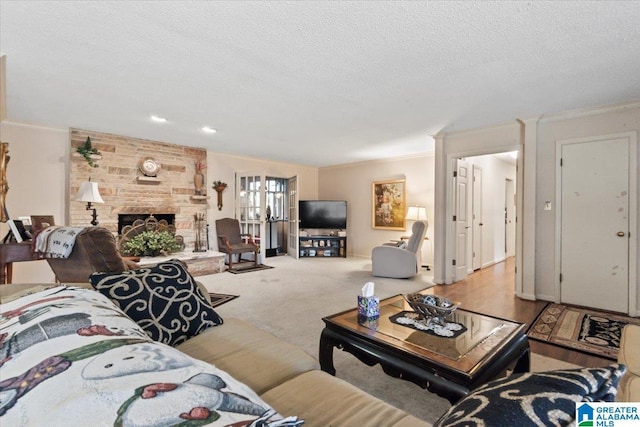 carpeted living room featuring a stone fireplace, french doors, a textured ceiling, and ornamental molding