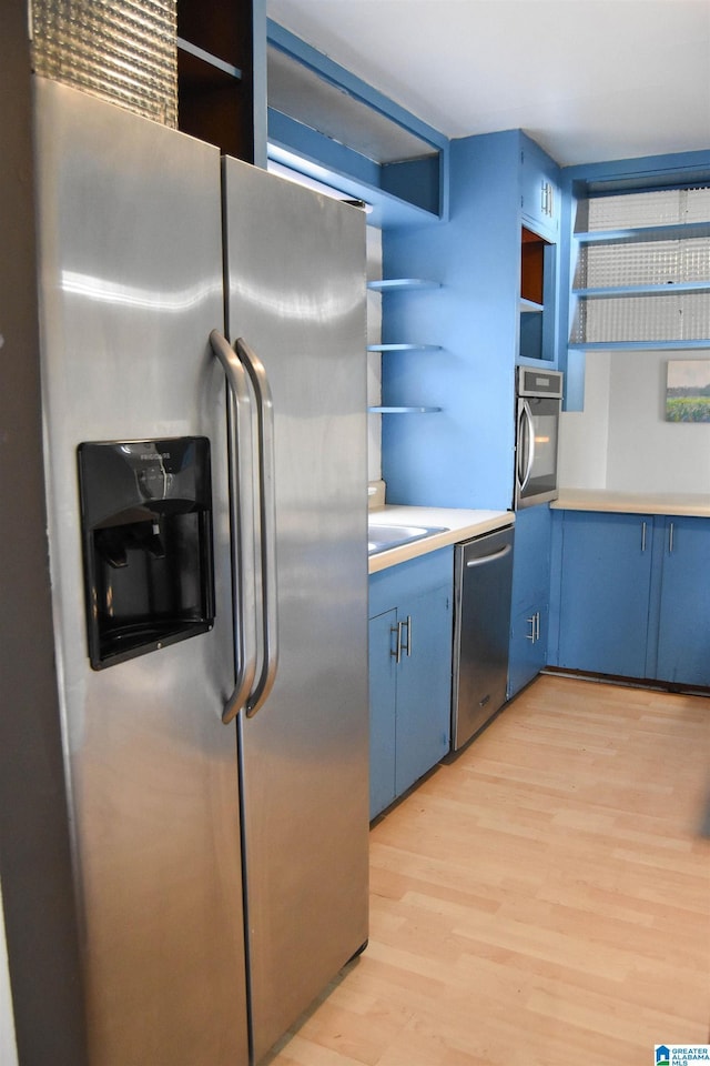 kitchen with blue cabinetry, sink, light hardwood / wood-style floors, and appliances with stainless steel finishes