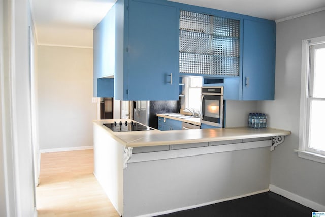 kitchen featuring oven, blue cabinets, a healthy amount of sunlight, and black electric cooktop