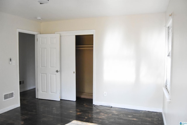 unfurnished bedroom with a closet and dark wood-type flooring