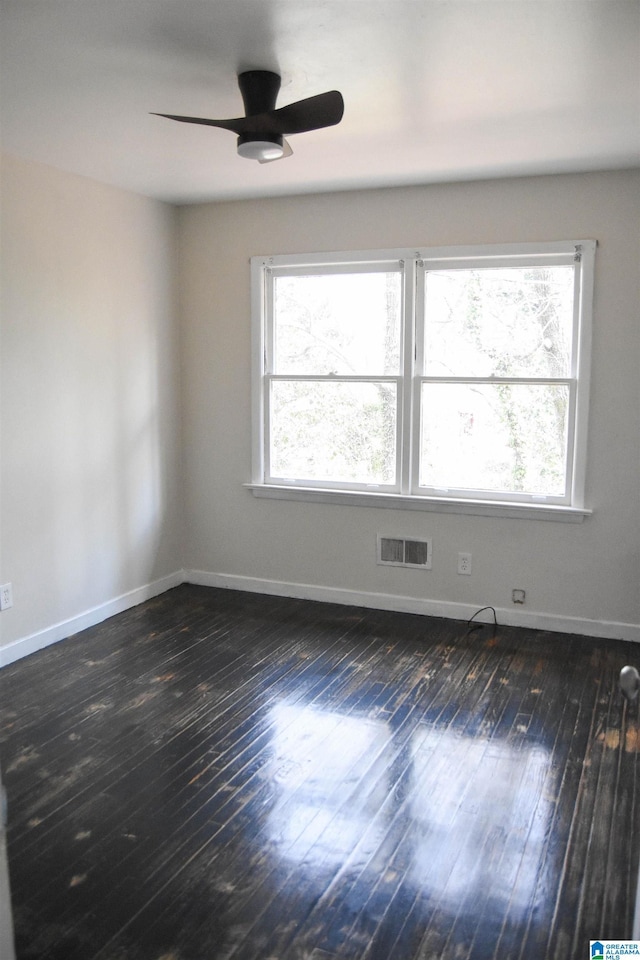 empty room with dark hardwood / wood-style floors, a healthy amount of sunlight, and ceiling fan