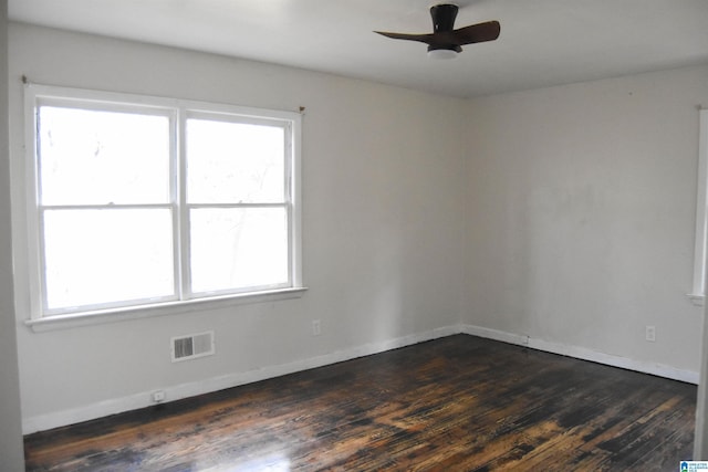 spare room featuring a wealth of natural light, ceiling fan, and dark wood-type flooring