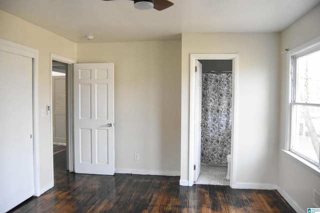 unfurnished bedroom with connected bathroom, ceiling fan, and dark wood-type flooring