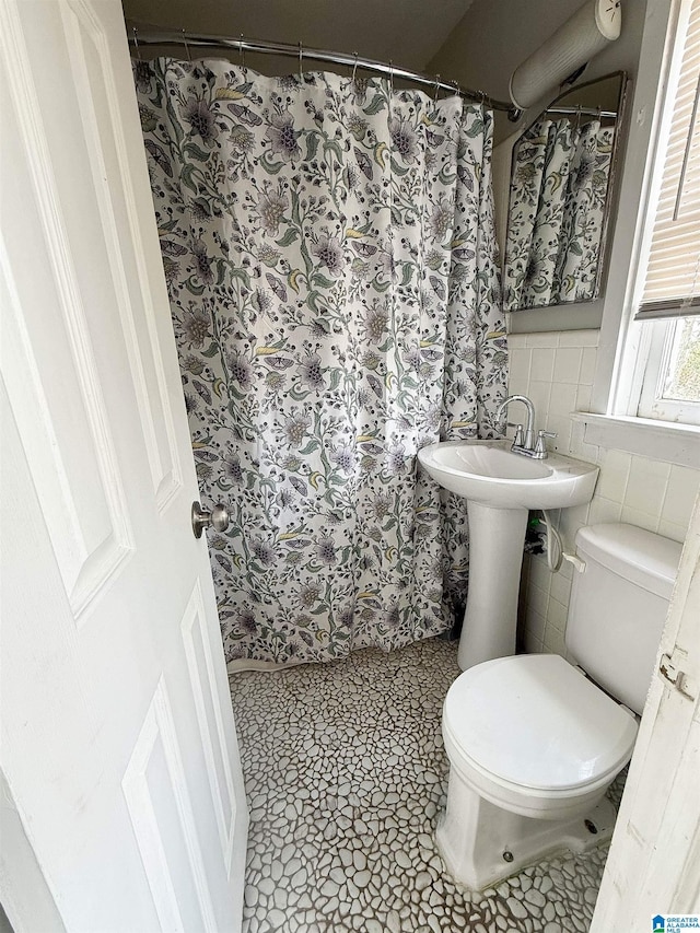 bathroom with tile patterned floors, toilet, and tile walls