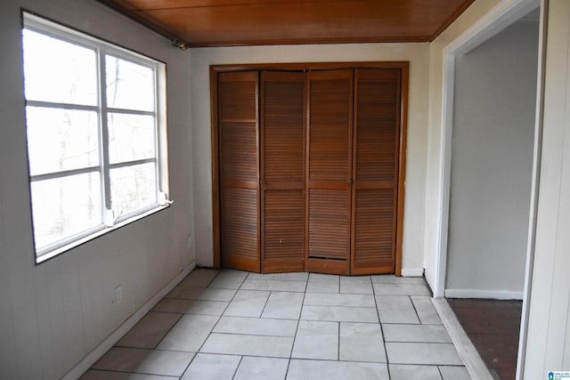 unfurnished bedroom with light tile patterned floors, a closet, and wood ceiling