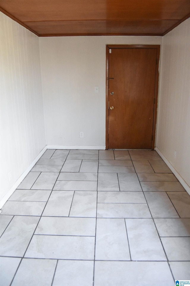 tiled spare room featuring wood ceiling