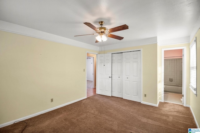 unfurnished bedroom featuring carpet flooring, ensuite bath, ceiling fan, and a closet