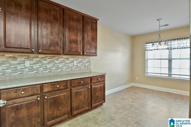 kitchen featuring pendant lighting, tasteful backsplash, dark brown cabinetry, and a chandelier