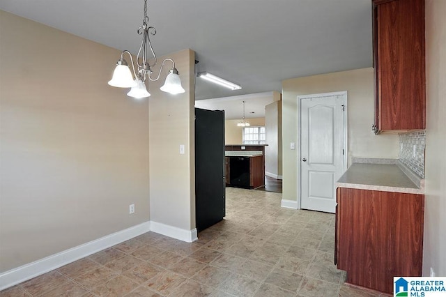 kitchen featuring pendant lighting, black fridge, an inviting chandelier, and tasteful backsplash