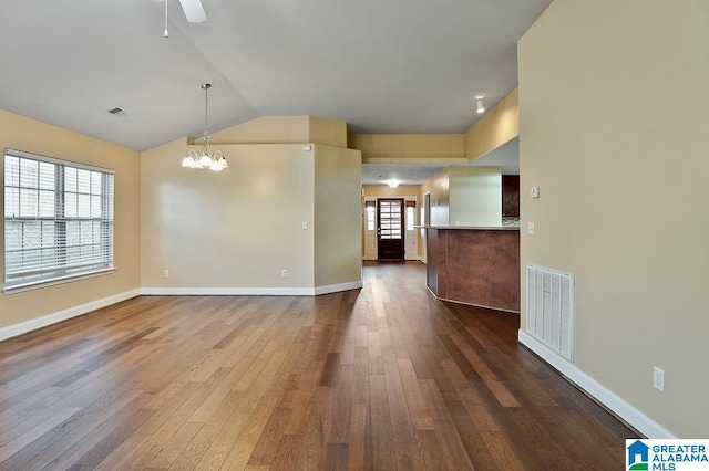 unfurnished living room with ceiling fan with notable chandelier, dark hardwood / wood-style flooring, and lofted ceiling