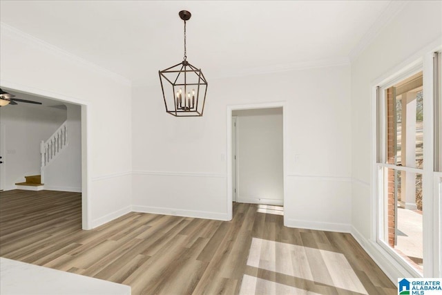 unfurnished dining area with ceiling fan with notable chandelier, wood-type flooring, and ornamental molding