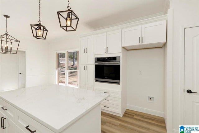 kitchen with decorative light fixtures, oven, crown molding, light stone countertops, and white cabinets