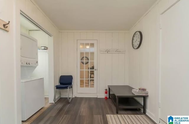 mudroom featuring crown molding, wooden walls, dark hardwood / wood-style floors, and stacked washer / dryer