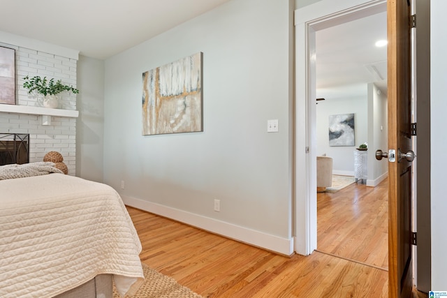 bedroom featuring a brick fireplace and wood-type flooring