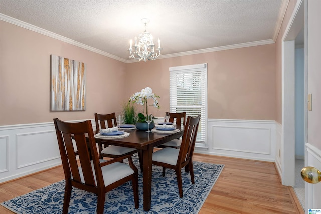 dining area with hardwood / wood-style floors, a textured ceiling, crown molding, and a chandelier