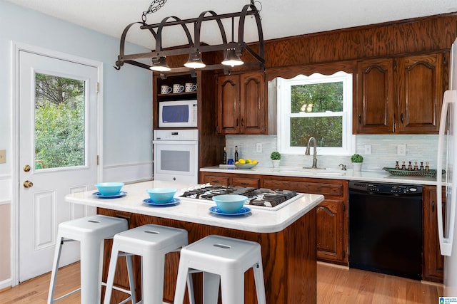 kitchen with a kitchen bar, white appliances, a center island, and hanging light fixtures