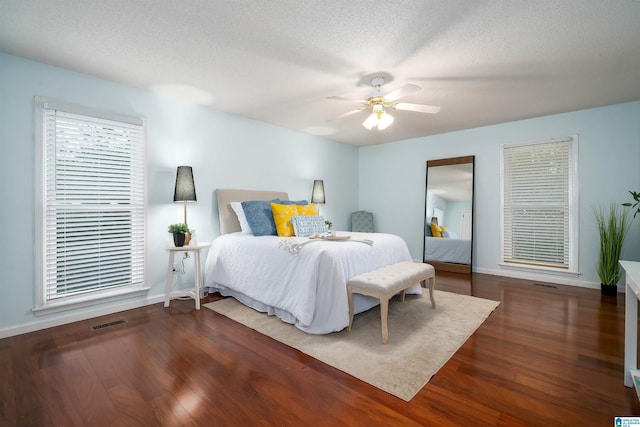 bedroom featuring ceiling fan, dark hardwood / wood-style floors, and a textured ceiling