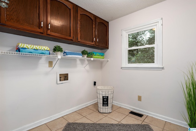 clothes washing area featuring cabinets, hookup for a washing machine, a textured ceiling, and light tile patterned floors