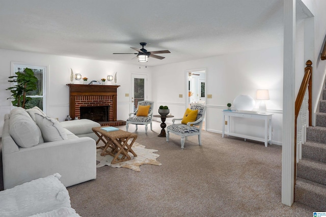 carpeted living room featuring a brick fireplace and ceiling fan